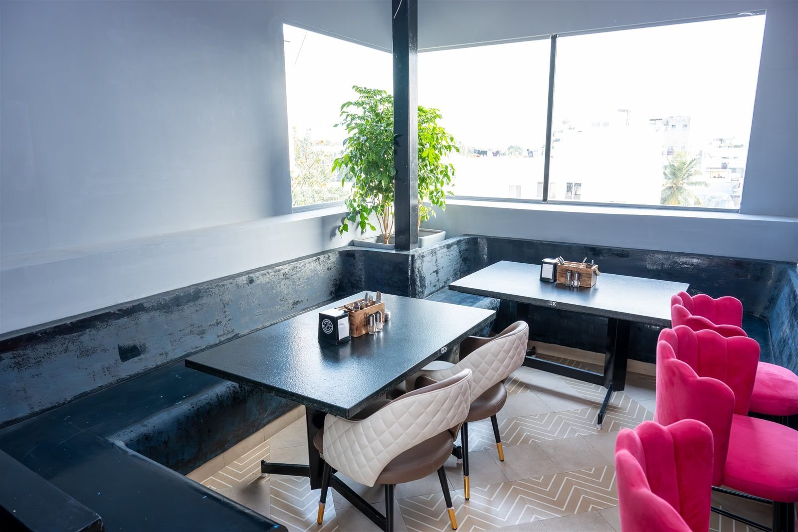 Tables by a large window with pink chairs
