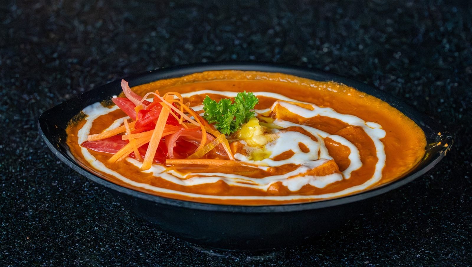 A bowl of orange curry finished with cream