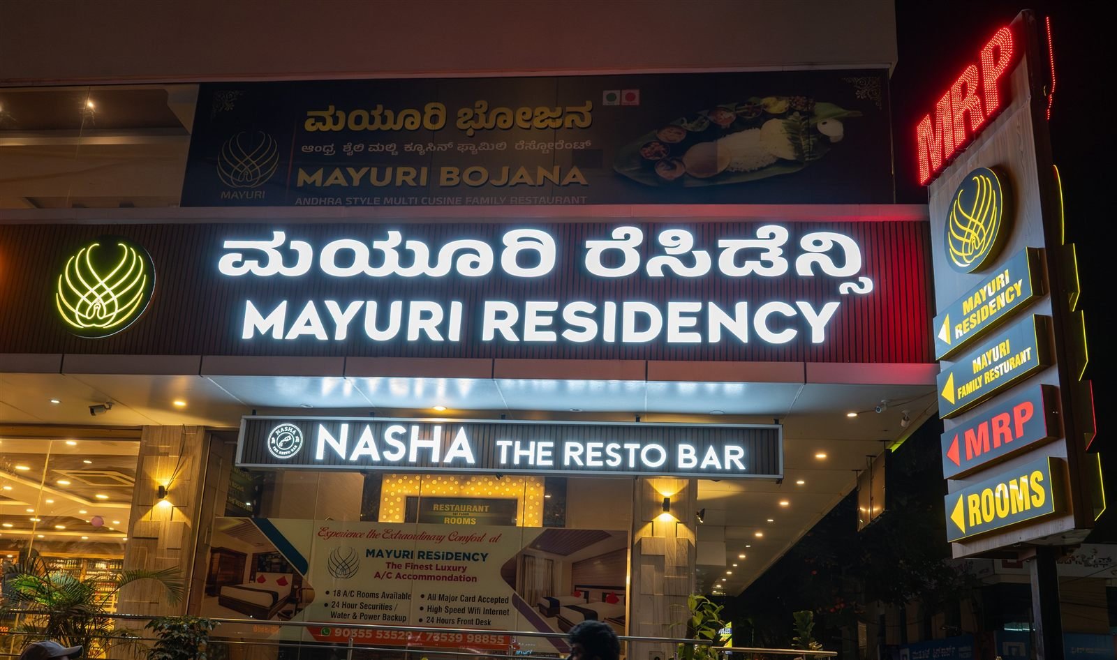 The lit Nasha The Resto Bar sign at the Mayuri Residency entrance at night
